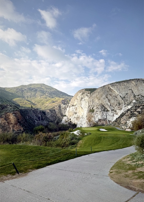 A green tucked beneath a canyon cliff