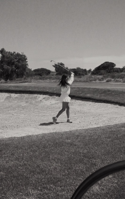 Golfer mid-swing from a bunker